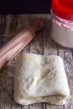 two uncooked pizza doughs sitting on top of a wooden table next to a rolling pin