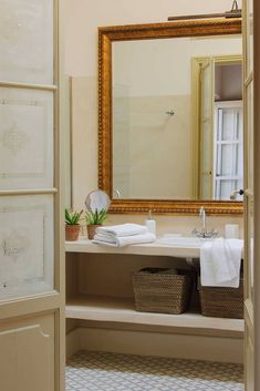 a bathroom with a sink, mirror and towels on the shelf in front of it