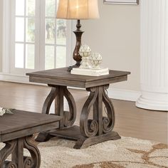 a wooden table sitting on top of a white rug next to a lamp and window