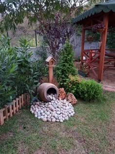 there is a birdhouse in the middle of some rocks and plants on the ground