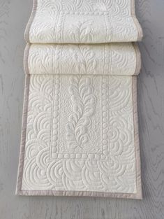 two white quilted bedspreads on top of each other