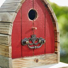 a birdhouse with a red door and metal handle