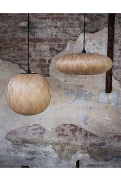 two wooden lamps hanging from the ceiling next to a brick wall