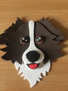 a brown and white dog's face is made out of paper on a wooden surface