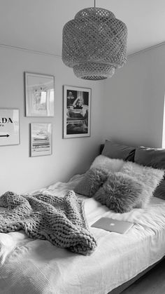 black and white photograph of a bed with pillows, blankets and pictures on the wall