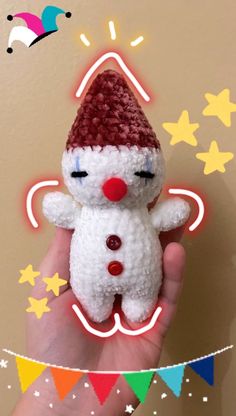 a hand holding a small white stuffed animal with a red hat on it's head