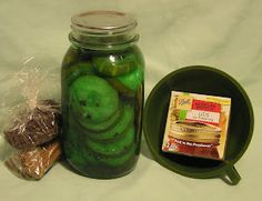 pickles in a glass jar next to a green plate and bag of peanut butter