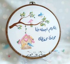 the embroidery is hanging from the hoop with birds and a birdhouse on it's side