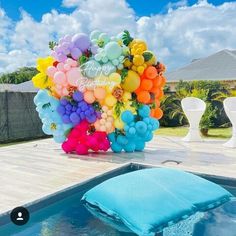 balloons are floating in the air next to a pool with a blue sheet on it