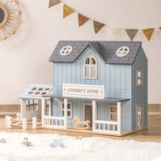 a blue doll house sitting on top of a wooden floor next to a wall clock