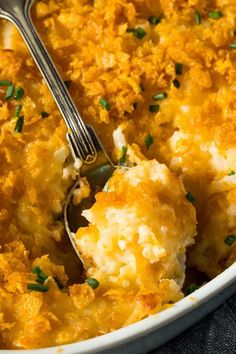 a casserole dish filled with mashed potatoes topped with green onions and parsley