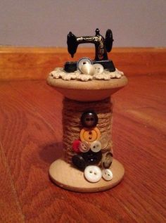 a sewing machine is sitting on top of a wooden table with buttons and yarn around it