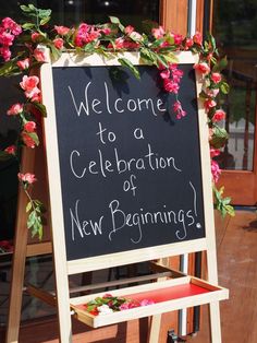 a welcome sign with pink flowers on it in front of a storefront window that says, welcome to a celebration of new beginnings