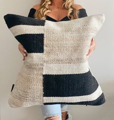 a woman holding a black and white pillow