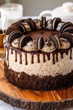 a chocolate cake with oreo cookies and cream drizzled over it on a wooden platter