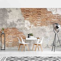 a brick wall with white chairs and a table next to it in front of a black and white rug