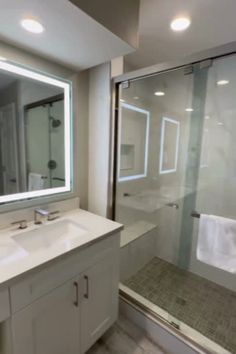 a bathroom with two sinks and a large mirror over the shower area, along with a walk in shower