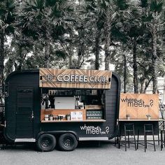 the coffee truck is parked in front of some tables with chairs and trees behind it