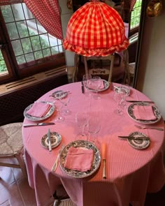 the table is set with plates, silverware and an orange hat on top of it