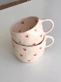 two white cups with hearts on them sitting on a table