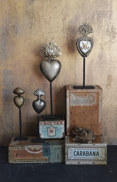 three metal hearts sitting on top of boxes next to each other and one is in the shape of a heart