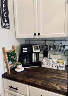 a kitchen with white cabinets and wooden counter top next to a black and white sign