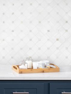 a tray with some cups on it in front of a tiled wall and counter top