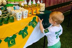 a little boy standing in front of a table filled with cupcakes and popcorn