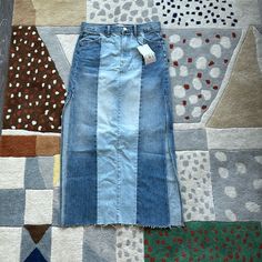 a blue jean skirt laying on top of a patchwork rug