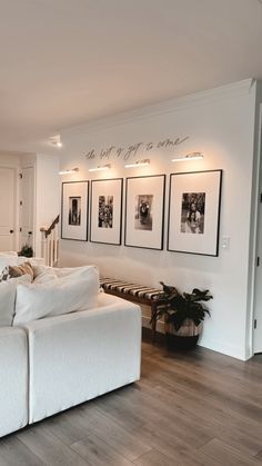 a large white couch sitting in a living room next to a wooden floor and two pictures on the wall