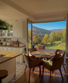 a kitchen with a table and chairs in front of a sliding glass door that looks out onto the mountains