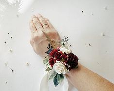 a person's hand with a flower wrist corsage