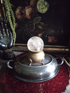 a silver tea pot sitting on top of a red doily next to a painting