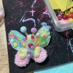 there is a small colorful butterfly on the table next to some beads and other things