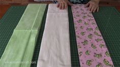 a person cutting fabric with scissors on top of a green mat and another piece of cloth next to it