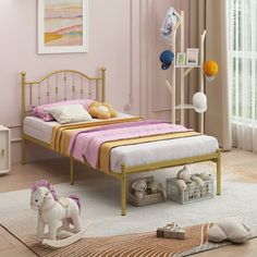 a child's bedroom with pink walls and gold bed frame, toy horse on the floor