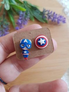 someone is holding two earrings with captain america designs on them, one has a shield and the other has a star