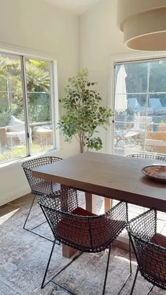 a dining room table with four chairs and a potted plant in the center area