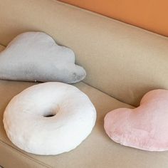 two pillows sitting on top of a couch next to a pillow shaped like a heart