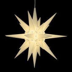 a white light hanging from the ceiling in front of a black background with an ornament shaped like a star