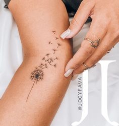 a woman's arm with a dandelion tattoo on the back of her leg