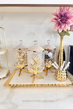 decorative items displayed on white marble countertop with pink flower in vase and gold accents