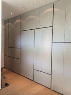 an empty room with white cabinets and wood flooring