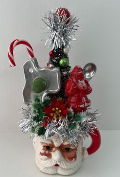 a santa clause mug with candy canes and other holiday decorations on it's head