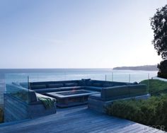 a couch sitting on top of a wooden deck next to the ocean