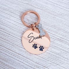 a dog's name and paw prints on a rose gold plated keychain