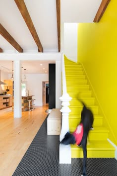 a person is running down the stairs in a room with yellow walls and black flooring