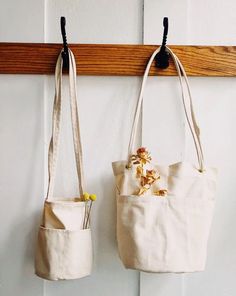 two bags hanging on a wall with flowers in them