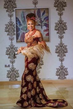 a woman in a red and gold dress is holding a feathered fan while posing for the camera