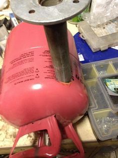 a red object sitting on top of a table next to other tools and materials in plastic containers